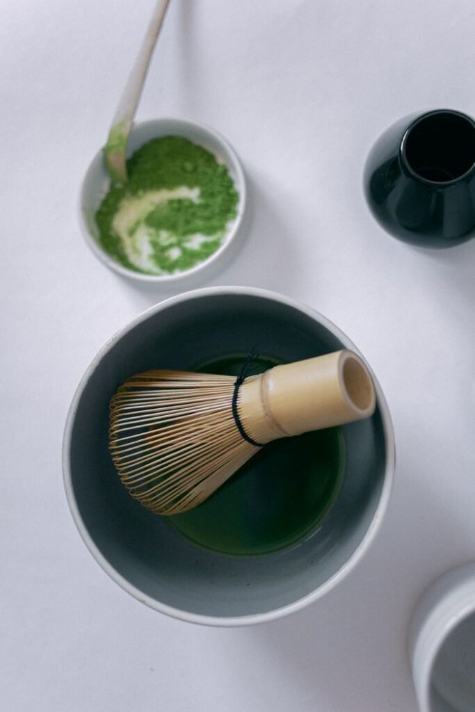 Top view of bamboo whisk and matcha in ceramic bowl, ideal for tea-related themes.